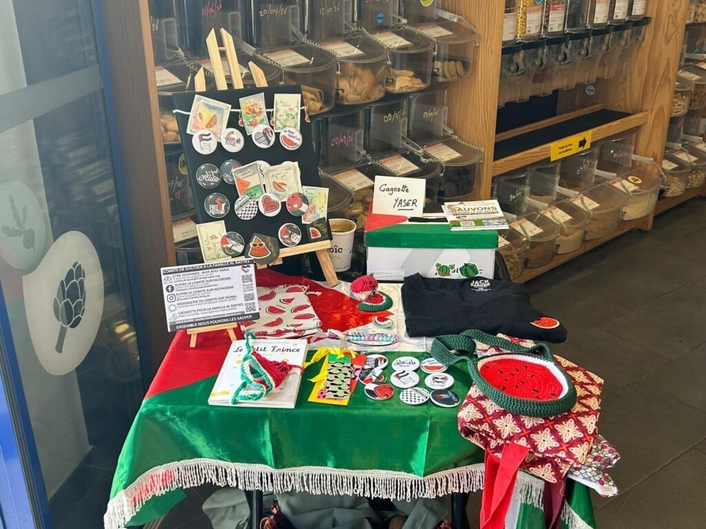 Stand solidaire installé dans un commerce de vrac en Bretagne, avec créations bénévoles et boîte à dons.